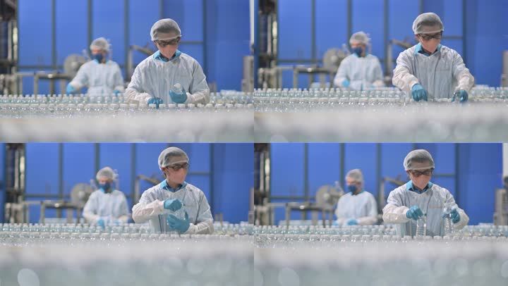 2名中国亚裔饮用水厂生产线工人,戴着PPE,每天检查水瓶